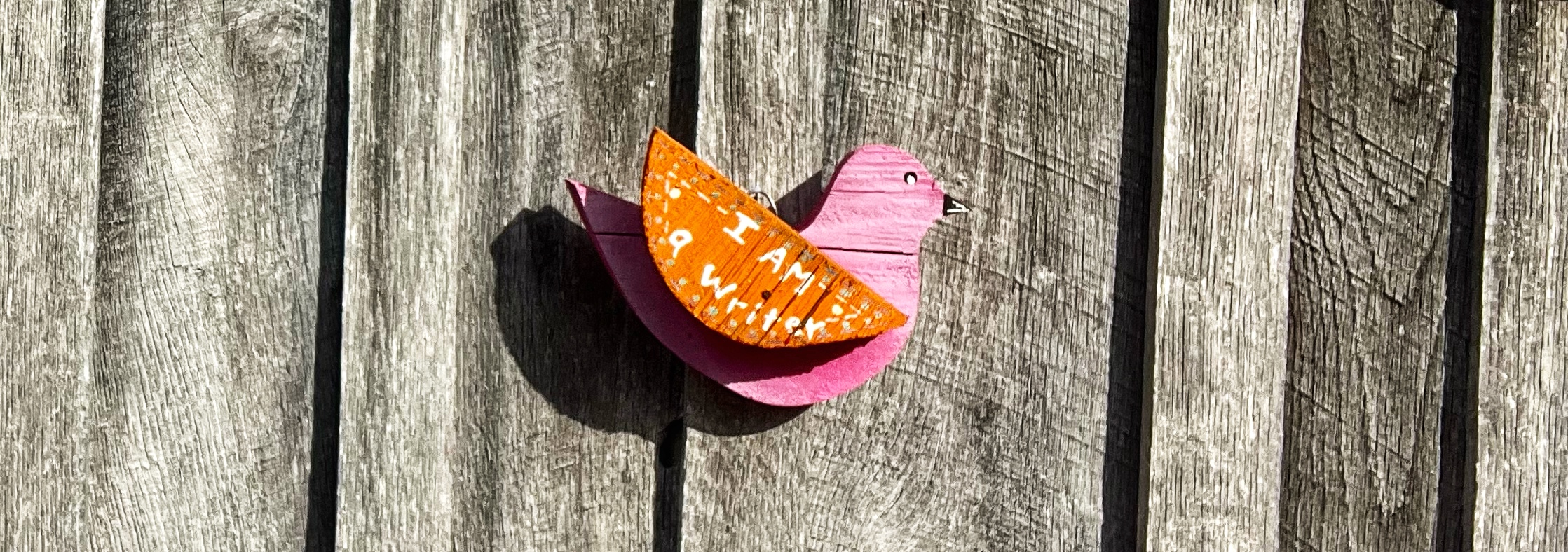 A wooden bird with "I am a writer" painted on its wing.